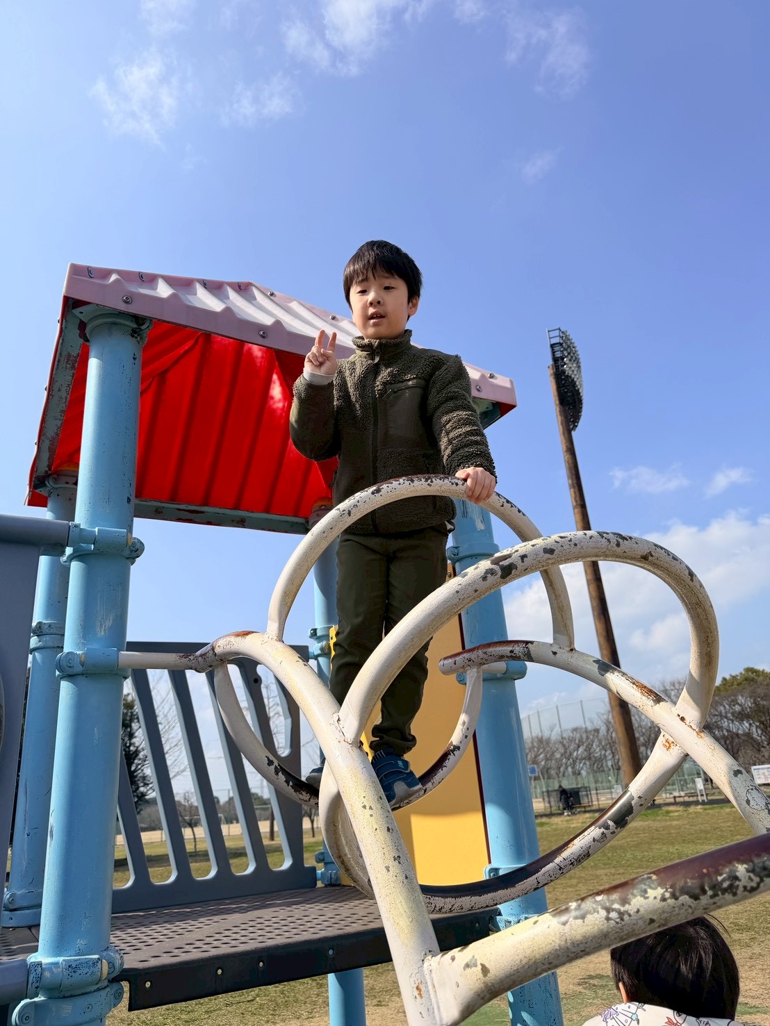 公園の遊具で達成感を見せるお子様